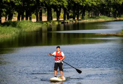 Pojke står på en paddelbräda och paddlar på Hjälmare kanal.